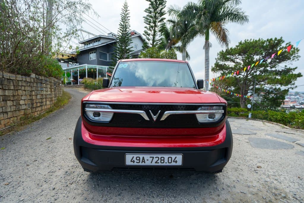 VinFast VF3 màu đỏ của Thuê Xe Đi đỗ trên con dốc rợp cây thông ở Đà Lạt